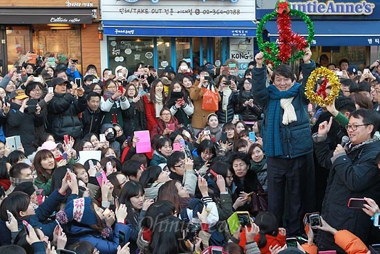  안철수 전 무소속 대선 예비후보가 11일 오후 서울 서대문구 이화여대 앞 번개 모임에서 투표도장 모양의 장식품을 들어보이며 문재인 민주통합당 대선후보 지원과 투표참여를 독려하자, 유권자와 지지자들이 휴대폰을 꺼내 안 후보의 모습을 촬영하고 있다.