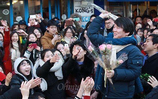 안철수 전 무소속 대선 예비후보가 11일 오후 서울 서대문구 이화여대 앞 번개 모임에서 문재인 민주통합당 대선후보 지원과 투표참여를 독려하며 환호하는 학생과 지지자들에게 장미꽃을 던져주고 있다.