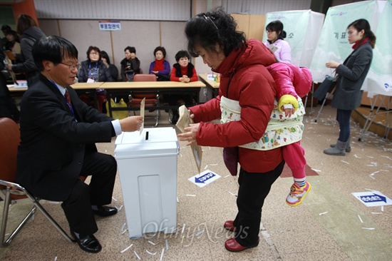 제18대 대통령선거 부재자투표 첫날인 13일 오후 서울 동작구청 지하1층에 설치된 부재자투표소에서 한 유권자가 어린아이를 업고 투표를 하고 있다.