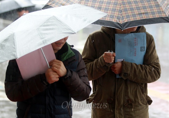 제18대 대통령선거 부재자 투표 마지막날인 14일 오전 비가 내리는 궂은 날씨에도 불구하고 서울 동작구청에 설치된 투표소에 투표용지가 든 봉투와 우산을 함께 든 젊은 유권자들이 도착하고 있다.