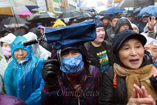14일 오전 경남 진주 장대동 중앙시장에서 열린 박근혜 새누리당 대선후보 유세에서 비가 내리자, 한 지지자가 접은 우산을 머리에 올려놓고 비를 맞으며 박 후보의 연설을 지켜보고 있다.