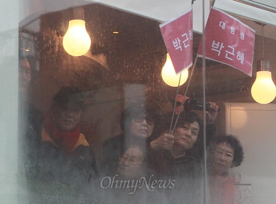 14일 오전 경남 진주 장대동 중앙시장에서 열린 박근혜 새누리당 대선후보 유세에서 비가 내리자, 유권자와 지지자들이 건물 유리창을 박 후보의 연설을 지켜보고 있다.