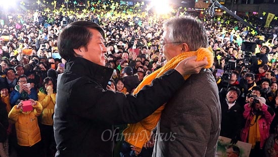 문재인 민주통합당 후보가 2012년 12월 15일 저녁 서울 광화문광장에서 유세를 하던 중 안철수 전 후보가 예정에 없이 깜짝 등장해 자신에 매고 있던 노란 목도리를 문 후보에게 둘러주고 있다. 
