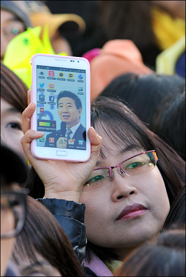 15일 오후 서울 광화문광장에서 열린 '앵콜 광화문 대첩' 현장을 찾은 한 시민이 스마트폰의 바탕화면으로 깔린 고 노무현 대통령의 사진을 흔들어 보이고 있다.