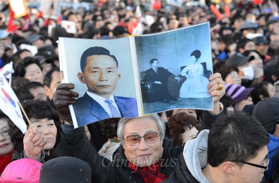  제18대 대통령 선거를 하루 앞둔 지난해 12월 18일 오후 부산 동구 부산역광장에서 열린 박근혜 새누리당 대선후보 유세에서 지지자들이 박정희, 육영수 사진을 들어보이며 박 후보를 응원하고 있다.