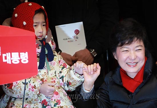 제18대 대통령 선거를 하루 앞둔 지난 2012년 12월 18일, 박근혜 새누리당 대선후보가 서울 종로구 광화문광장 유세에서 한 어린아이와 공약 약속을 다짐하며 손가락 약속을 하고 있다.

