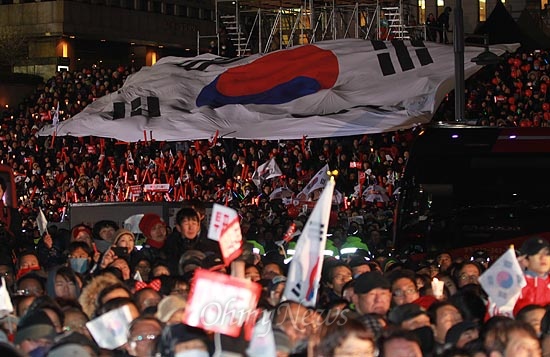 제18대 대통령 선거를 하루 앞둔 18일 오후 서울 종로구 광화문광장에서 열린 박근혜 새누리당 대선후보 유세에서 가수 이미자씨가 애국가를 부르자, 지지자들이 대형 태극기를 펼쳐보이고 있다.