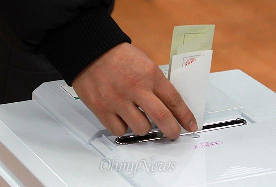 제18대 대통령선거 날인 19일 오전 서울 강남구 언주중학교에 마련된 삼성2동 제3투표소에서 유권자가 기표를 마친뒤 기표용지를 투표함에 넣고 있다.
