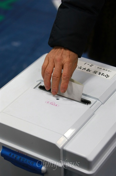 제18대 대통령선거날인 19일 오전 서울시 용산구 한강로동 제4투표소장에서 투표를 마친 유권자가 투표용지를 투표함에 넣고 있다.