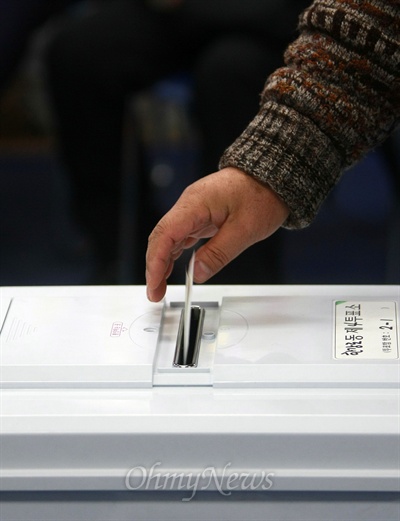 제18대 대통령선거날인 19일 오전 서울시 용산구 한강로동 제4투표소장에서 투표를 마친 유권자가 투표용지를 투표함에 넣고 있다.