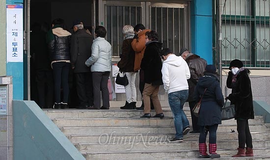제18대 대통령선거 날인 지난 19일 오후 서울 영등포구 여의도중학교에 마련된 여의도 제4투표소에서 유권자들이 투표를 하기 위해 건물 밖까지 길게 줄을 서서 기다리고 있다.