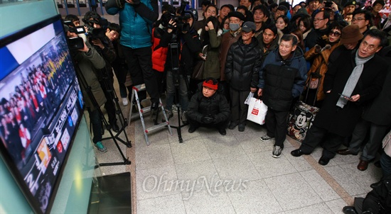 19일 오후 서울시 용산구 동자동 서울역에서 시민들이 출구조사발표 방송을 보고 있다.