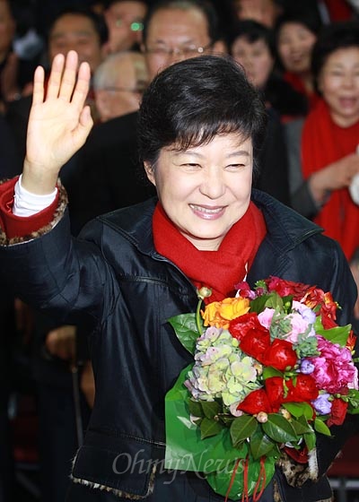 제18대 대통령 박근혜 당선자가 19일 오후 서울 여의도 새누리당사에 마련된 선거종합상황실에서 당선 축하 꽃다발을 건네받은 뒤 손을 들어보이고 있다.