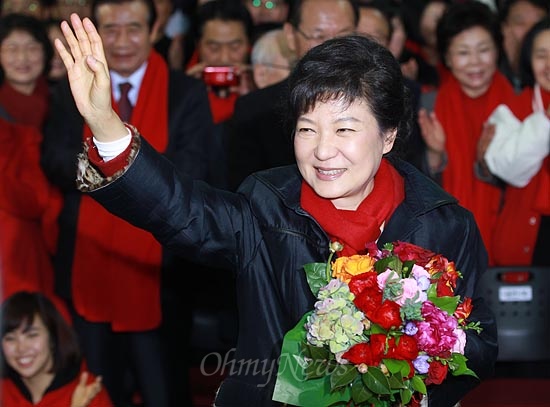 2012년 12월 19일, 제18대 대통령선거에서 당선이 확실시 되고 있는 박근혜 새누리당 대선후보가 서울 여의도 당사에 마련된 선거종합상황실에서 축하꽃다발을 건네받은 뒤 손을 들어보이고 있다.