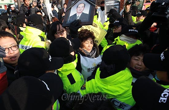 용산참사 희생자 고 이상림씨 부인 전재숙씨와 4주기 범국민추모위원회 회원들이 7일 오전 서울 종로구 삼청동 한국금융연수원 내 마련된 대통령직 인수위원회 앞에서 용산참사 진상규명과 구속철거민 사면을 촉구하는 기자회견을 하려하자, 경찰들이 이를 에워싸고 저지하고 있다.
