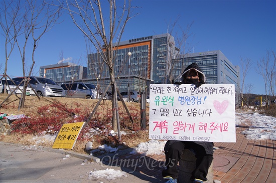 경북대병원 칠곡분원에서 해고된 노동자들이 원직복직을 요구하며 천막농성을 하고 있는 가운데 한 노동자가 피켓을 들고 1인시위를 벌이고 있다.