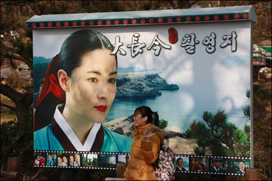 젊은 중국 관광객으로 보이는 한 여성이 대장금 촬영지에서 주인공 장금이 앞에서 사진을 찍고 있다. 