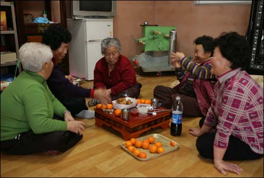 오후 내내 조진순 씨의 한옥에서 쌀엿을 만든 할머니들이 모여앉아 새참을 즐기고 있다. 새참으로 통닭과 감귤이 올라와 있다.