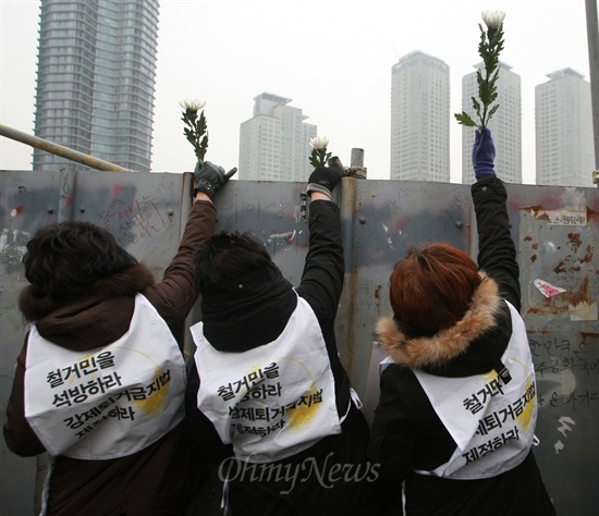  용산참사 유가족들이 14일 오전 서울 용산구 용산참사 현장 남일당터에서 열린 '용산참사 4주기 범국민추모주간 선포 기자회견'을 마치고 담벼락에 헌화를 하고 있다.