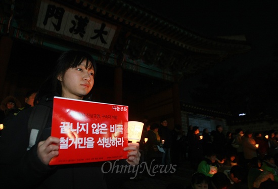 14일 오후 서울 대한문 앞에서 열린 '용산참사 4주기 추모미사'에 참가한 한 시민이 '끝나지 않은 비극 철거민을 석방하라'는 내용의 손피켓을 들고 있다.
