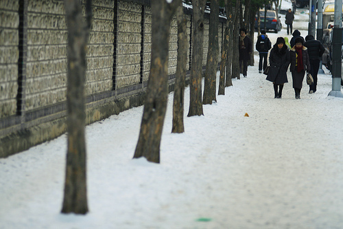 추운 날씨에 눈 쌓인 길을 걷고 있는 시민들