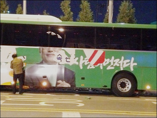 문재인 후보 사진이 래핑된 버스에 문 후보 사진을 당직자가 떼어내고 있다. 