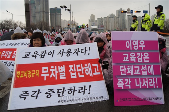  학교비정규직 경북대책위가 마련한 결의대회에 참가한 한 노동자가 "무차별 집단해고 즉각 중단하라", '이영우 교육감은 즉각 단체교섭에 나서라"는 피켓을 들고 있다.