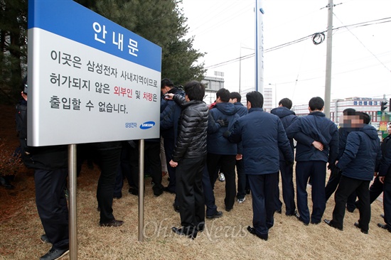 삼성전자 인간 바리케이드 불산누출 사고 은폐 규탄 기자회견에 참석한 시민단체 회원들이 삼성전자 정문앞까지 접근을 시도하자 삼성전자 직원들이 스크럼을 짜고 밀어내고 있다. 도로옆에는 '이곳은 삼성전자 사내지역이므로 허가되지 않은 외부인 및 차량은 출입할 수 없습니다'는 안내문이 세워져 있다.