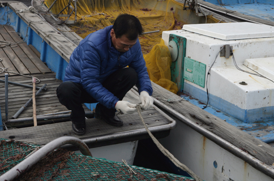 김양한 씨가 김양식장으로 나가기 위해 포구에 묶어놓은 선박의 줄을 풀고 있다.