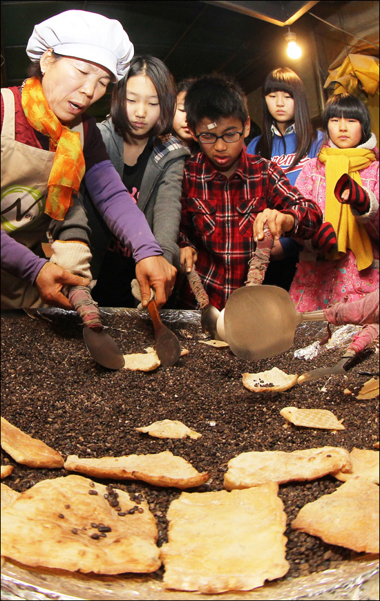  설 명절을 나흘 앞둔 6일 경남 함양군 지곡면 개평전통한옥마을 찾은 어린이들이 자갈에서 굽어내는 전통한과 만들기 체험을 해 보고 있다.
