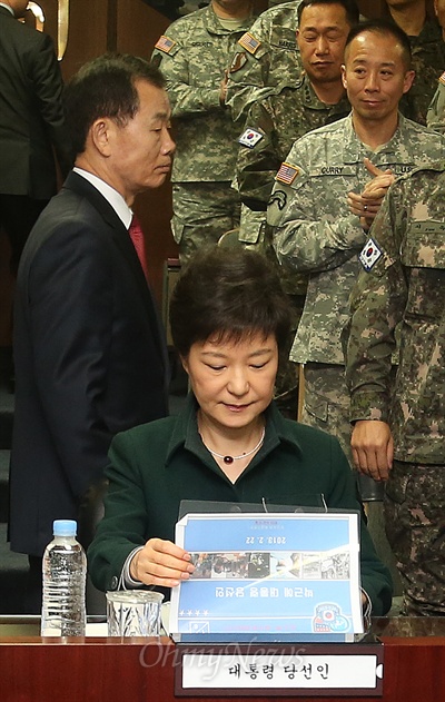 박근혜 대통령이 당선인 시절인 지난 2월 22일 오전 서울 용산 한미연합군사령부에 도착해 브리핑실에서 자료를 보는 동안 김병관 국방부 장관 내정자가 박 당선인 뒤로 지나가고 있다.