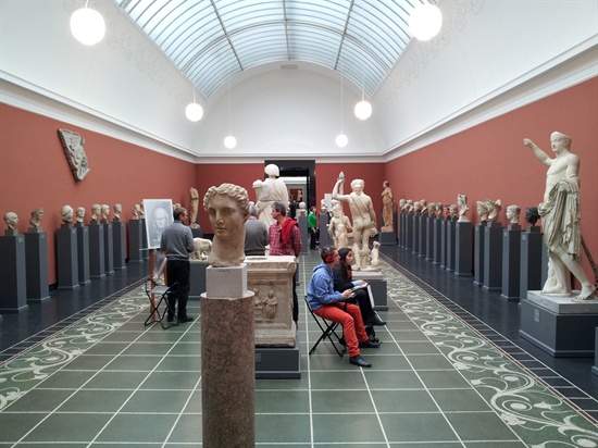 칼스버그 박물관 내의 그리스 로마시대 조각상, 학생들이 조각품 앞에서 데생을 하고 있다.