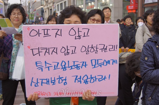 화점 앞에서 열린 세게여성의날 기념 대구경북여성대회에서 한 참가자가 '아프지 않고 다치지 않고 일할 권리'를 적은 피켓을 들고 서 있다.
