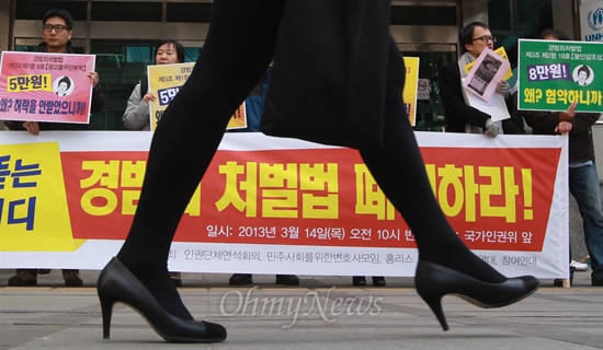 3월 14일 오전 서울 중구 국가인권위원회 앞에서 인권단체연석회의, 민주사회르위한변호사모임, 홈리스행동 회원들이 기자회견을 열고 경범죄처벌법 폐지를 촉구하고 있는 가운데, 한 시민이 짧은 치마를 입고 거리를 지나가고 있다.