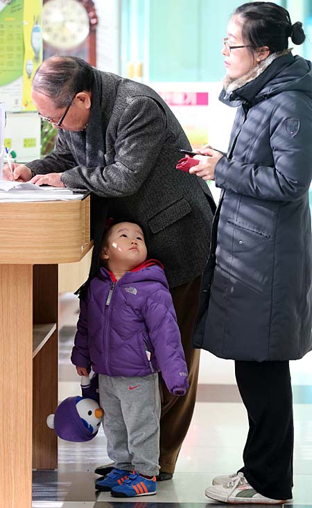 보육료·양육수당 지원 사전신청 첫날인 2월 4일 대전 유성구의 한 주민센터를 찾은 할아버지와 어엄마가 수당 신청에 앞서 관련 서류를 작성하고 있다. 
