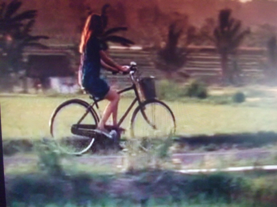 주인공 리즈(줄리아 로버트)가 발리에서 자전거를 타고 시골길을 달려가고 있다.