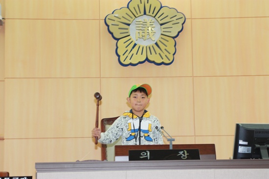 여수시의회를 방문한 여안초 6학년 신태양군이 시의회 의장석에서 지휘봉을 두드리고 있다.