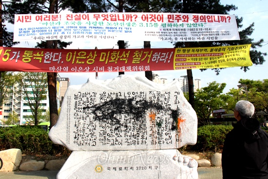 마산역광장에 세워진 이은상 시비 위에는 철거에 찬성하거나 반대하는 내용의 펼침막이 나란히 걸려 있다.