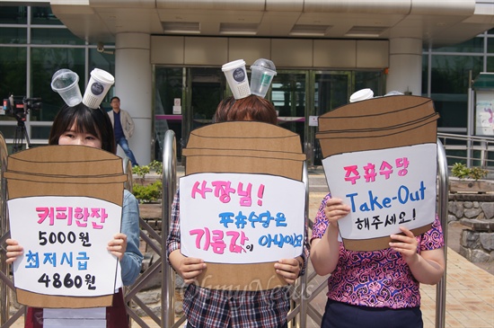 회원들이 커피전문점에서 최저임금법 위반과 주휴수당 미지급에 대해 항의하는 손피켓을 들고 있다.