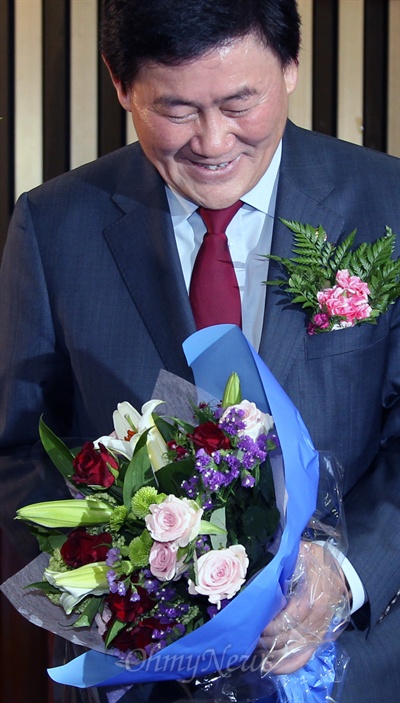 15일 새누리당의 새 원내대표로 선출된 최경환 의원이 꽃다발을 받아들고 환하게 웃고 있다. 