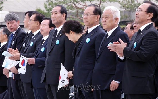 박근혜 전 대통령이 2013년 5월 18일 광주시 북구 운정동 국립 5·18민주묘지에서 열린 제33주년 5·18 민주화운동 기념식에서 인천 오페라합창단의 '임을 위한 행진곡' 합창이 시작되자 태극기를 든 채 자리에서 일어나고 있다.