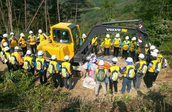 한국전력공사가 밀양 송전탑 공사를 재개한지 사흘째인 지난 달 22일 주민들이 공사 저지를 위해 중장비 쪽에 앉아 있다. 사진은 한국전력 직원들이 주민들을 에워싸고 있는 모습.
