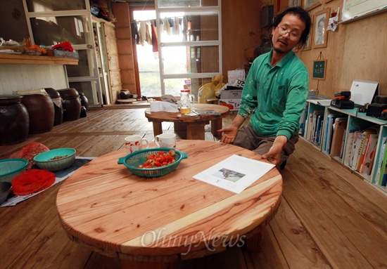 허윤석씨가 전선이 감겨져 있던 나무판 가져다가 만든 원형 탁자를 보여주며 재활용의 기쁨에 대해 이야기하고 있다.