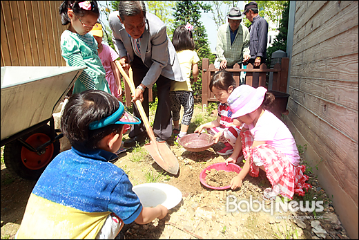 대전 테크노밸리 공동직장어린이집 뿌리와새싹어린이집 아이들이 모내기를 할 때 필요한 흙을 담기 위해 그릇을 내밀자, 할아버지가 삽으로 흙을 퍼주고 있다. 