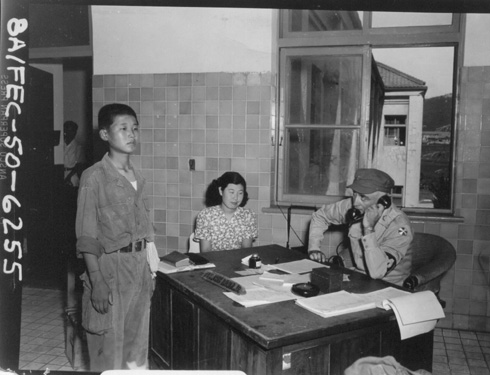 한 어린 인민군 포로가 포로신문관 앞에서 조사를 받고 있다(1950. 8. 18.).