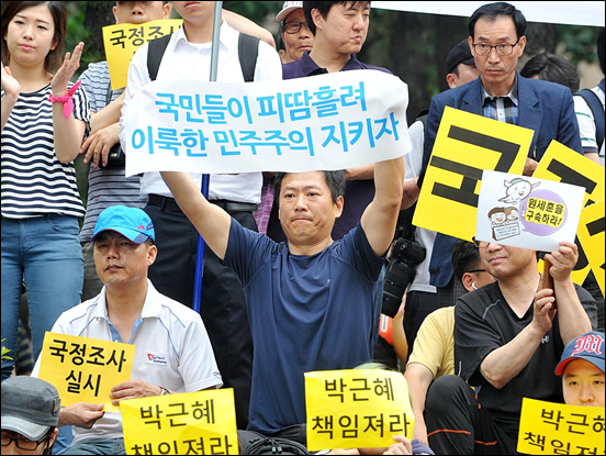  22일 오후 서울 청계광장에서 개최된  '국정원 대선개입 규탄 촛불문화제'에서 한 참가자가 '국민들이 피땀흘려 이룩한 민주주의 지키자'라고 적힌 현수막을 힘차게 흔들어 보이고 있다.