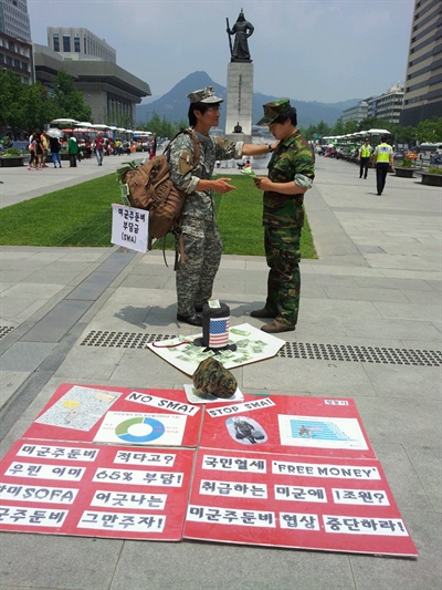 '평화와 통일을 여는 사람들'은 서울 광화문 광장에서 지난해 5월 22일 '불법부당한 방위비분담금(미군주둔경비)를 위해 미군에게 국민혈세 갖다 바치는 한국 정부당국을 풍자' 퍼포먼스를 펼쳤다. 