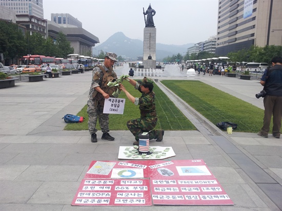 '평화와 통일을 여는 사람들'은 서울 광화문 광장에서 지난 5월 22일 '불법부당한 방위비분담금(미군주둔경비)를 위해 미군에게 국민혈세 갖다 바치는 한국 정부당국을 풍자' 퍼포먼스를 펼치고 있다. 