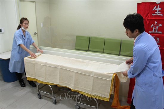 부산의료원 장례식장의 민상호, 박선영 장례지도사가 마지막으로 고인이 누울 관에 베를 덧대고 있다. 
