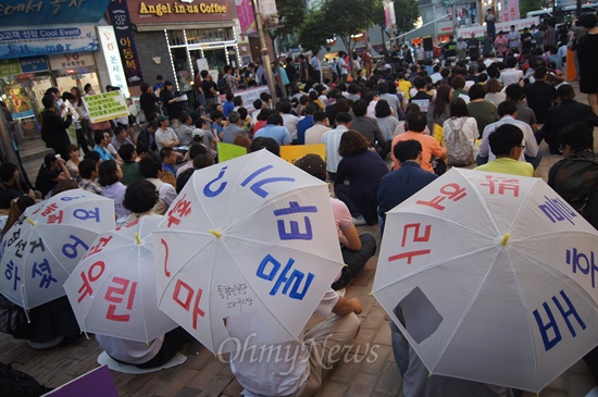 28일 오후 대구시 중구 동성로 한일극장 앞에서 열린 국정원 불법 정치개입 규탄대회에 참가한 일부 참가자가 비닐우산에 규탄하는 글자를 붙이고 앉아있다.